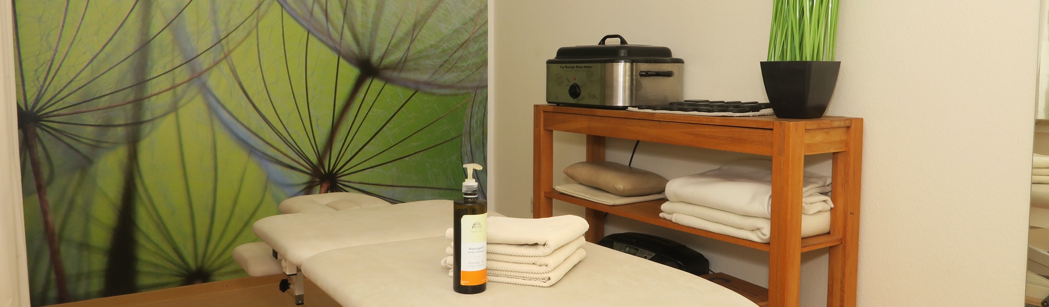 Wellness-Raum mit Massage-Liege, Hot-Stone-Heizgerät und Pflanzen